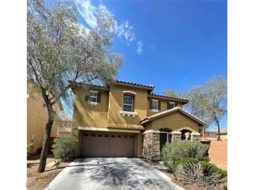 Two-story home featuring a two-car garage, stone accents and desert landscaping at 8768 Charm Canyon Ave, Las Vegas, NV 89178