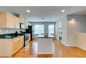Bright kitchen features stainless appliances, wood floors and light cabinets with island at 9050 W Tropicana Ave # 1053, Las Vegas, NV 89147