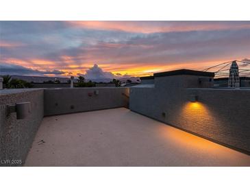 Open rooftop patio with lights offering a stunning view of the colorful sunset over distant mountains at 9050 W Tropicana Ave # 1053, Las Vegas, NV 89147