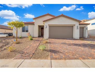 Charming single-story home featuring a brick driveway, two-car garage, desert landscaping, and a tile roof at 647 Quarry Pass, Mesquite, NV 89034