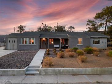 Charming single-story home featuring a well-maintained front yard with a cozy front porch seating area at 650 Arizona St, Boulder City, NV 89005