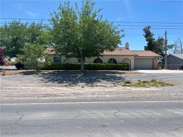 Charming single-story home featuring a tile roof, well-maintained landscaping, and an attached two car garage at 881 E Calvada Blvd, Pahrump, NV 89048