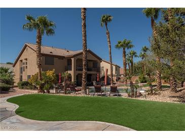 Beautiful backyard with pool, lawn, and palm trees; perfect for outdoor entertaining at 9012 Alpine Peaks Ave, Las Vegas, NV 89147