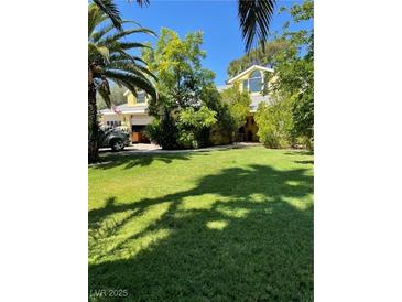 Landscaped front yard with a well-maintained lawn and mature trees, offering curb appeal at 1385 Ringe Ln, Las Vegas, NV 89110