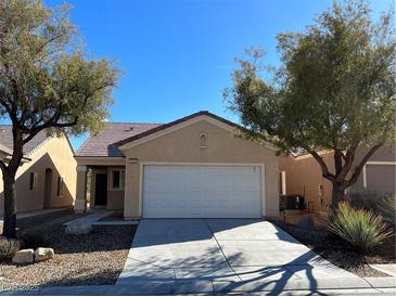 Tan single-story home with a two-car garage, desert landscaping and a clear blue sky at 3029 Frigate Way, North Las Vegas, NV 89084