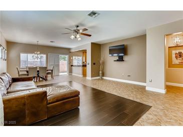 Bright living room featuring tile and hardwood floors, ceiling fan, and an adjacent dining area at 10601 India Hawthorn Ave, Las Vegas, NV 89144