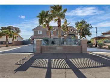 Two-story home with palm trees, gated entrance, and a long driveway at 131 Beesley Dr, Las Vegas, NV 89110