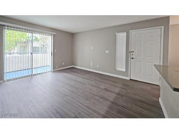 Bright living room with sliding glass doors, wood-look flooring, and neutral paint, ready for your personal touches at 3038 Tarpon Dr # 203, Las Vegas, NV 89120