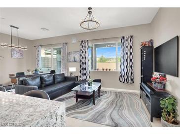 Cozy living room with a black leather sofa, area rug, and view to the backyard at 12426 Oregon Cherry Ave, Las Vegas, NV 89138
