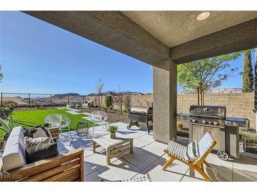 Relaxing covered back patio featuring a built-in grill, stylish furniture, and mountain views at 12532 Blissful Sky St, Las Vegas, NV 89138
