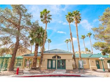 Charming community clubhouse with palm trees, green tile roof, gated entrance, and well-maintained landscaping at 1400 Jamielinn Ln # 104, Las Vegas, NV 89110