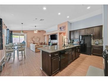 Open concept kitchen features a center island, stainless steel appliances, and seamlessly connects to the dining and living areas at 2104 Leatherbridge Ct, North Las Vegas, NV 89081