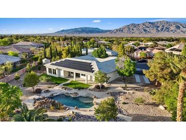 Expansive backyard featuring a pool, desert landscaping, and solar panels with mountain views at 6907 Kelp Ledge Ct, Las Vegas, NV 89131