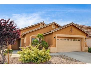 Charming single-story home with a two-car garage, desert landscaping, and a terracotta-colored exterior at 900 Royal Plum Ln, Las Vegas, NV 89144