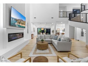 Bright, open living room features modern fireplace, entertainment center, and elegant staircase to the second floor at 5225 Villa Dante Ave, Las Vegas, NV 89141