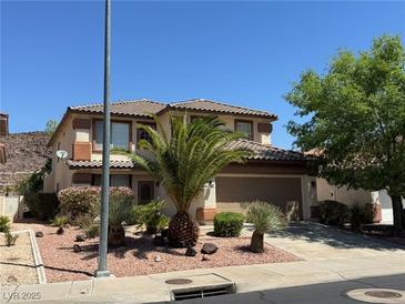 Two-story home with a well-manicured front yard featuring desert landscaping and mature palm trees at 96 Saint Johns Wood Ave, Henderson, NV 89002