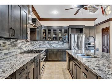 Modern kitchen featuring gray cabinets, granite countertops, stainless steel appliances, and stone backsplash at 2051 Saginaw Ave, Pahrump, NV 89048