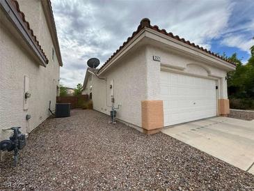 Tan home featuring a two car garage, gravel yard, and an orange tiled roof at 2571 Swans Chance Ave, Henderson, NV 89052