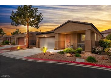 Charming single-story home featuring a well-maintained front yard and inviting covered porch at sunset at 601 Bear Grass St, Las Vegas, NV 89144