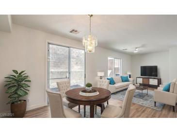 Bright living room with dining area, wood floors, modern lighting and sliding glass door to a private backyard at 632 Twilight Blue Ave, North Las Vegas, NV 89032