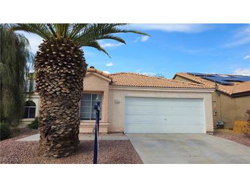 Charming single-story home with a two-car garage and a well-maintained front yard with gravel and mature palm tree at 7053 Magic Moment Ln, Las Vegas, NV 89119