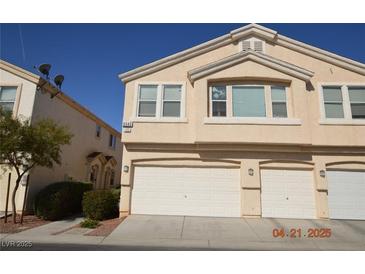 Beige two-story townhome featuring a multi-car garage and well-maintained landscaping at 9343 Leaping Deer Pl # 103, Las Vegas, NV 89178