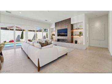 Bright living room featuring modern fireplace, built-in shelving, and access to the backyard pool at 10528 Garden Light Dr, Las Vegas, NV 89135