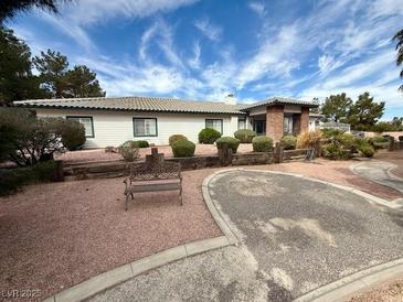 Charming ranch-style home featuring a well-maintained yard, mature landscaping, and a cozy front bench at 10561 Rancho Destino Rd, Las Vegas, NV 89183