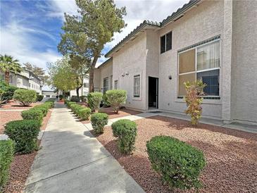 Apartment exterior featuring well-maintained landscaping, gravel and shrubs, with a lovely sidewalk at 2471 Old Forge Ln # 103, Las Vegas, NV 89121