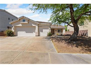 Charming single-story home featuring a three-car garage and beautifully landscaped front yard with mature shade tree at 51 La Fiesta St, Henderson, NV 89012