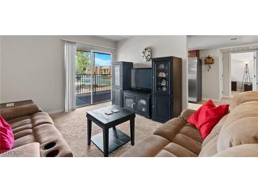 Open-concept living room features a slider to a balcony, neutral decor, and dark wood entertainment center at 5185 Indian River Dr # 229, Las Vegas, NV 89103