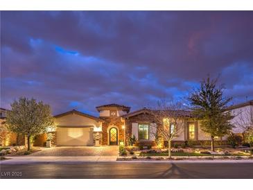 Charming single story home with stone accents, a three car garage and manicured landscaping at twilight at 62 Grand Masters Dr, Las Vegas, NV 89141
