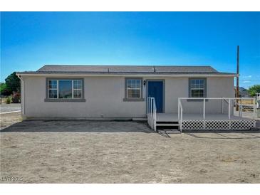 Cozy single-story home with blue door and a white-railed deck under a clear blue sky at 1450 Fern St, Pahrump, NV 89060
