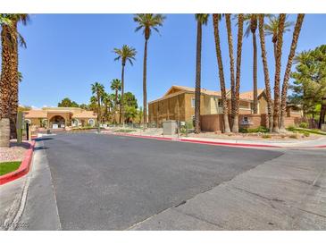 Exterior street view of a well-maintained condo complex with lush landscaping and palm trees against a clear blue sky at 2120 Ramrod Ave # 513, Henderson, NV 89014