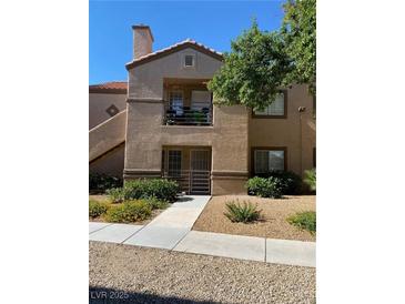 Beige two-story home featuring a balcony, landscaped yard, and tile roof under a bright blue sky at 3450 Erva St # 167, Las Vegas, NV 89117