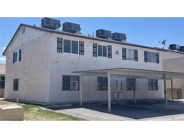 A multi-Gathering building featuring a stucco exterior, bars on lower windows, and a covered parking area at 5275 Hagemann Ln, Las Vegas, NV 89110