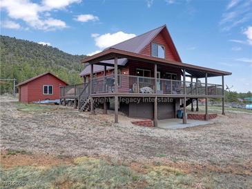 Charming cabin with a large deck and a separate garage, nestled in a mountainous landscape at 660 E Aspen Meadow Dr, Mammoth Creek, UT 84735