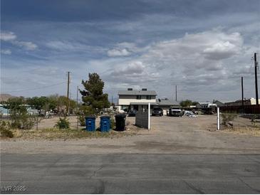 Exterior view of a two-story home with a large, dirt front yard and several parked vehicles at 664 Spring Rd, Indian Springs, NV 89018