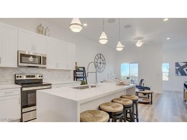 Modern kitchen boasts white cabinets, stainless steel appliances, and an island with bar seating at 1181 Blossom Point St, Las Vegas, NV 89135