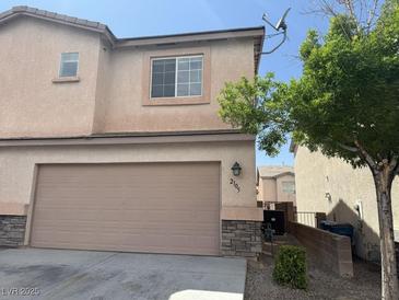 Two-story house featuring a two car garage, desert landscaping, and beige stucco siding at 2105 William Holden Ct, Las Vegas, NV 89142