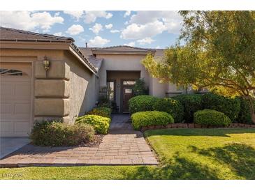 Beautiful single-story home featuring well-manicured landscaping and a charming brick walkway to the front door at 240 Jumping Springs Pl, Henderson, NV 89012
