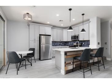 Modern kitchen features stainless steel appliances, gray cabinets, and a stylish breakfast bar with unique wood accents at 689 Principle Point Ave, Henderson, NV 89012