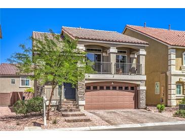 Inviting two-story home featuring a charming balcony, stone accents, and a well-manicured front yard at 7732 Canon Walk St, Las Vegas, NV 89139