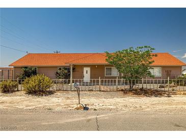 Single story home featuring a well-maintained yard, complemented by mature landscaping, and a charming fence at 2090 S Ambush St, Pahrump, NV 89048