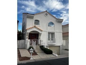 Charming two-story home featuring a well-manicured yard, a unique facade, and attached garage at 2857 Queens Courtyard Dr, Las Vegas, NV 89109