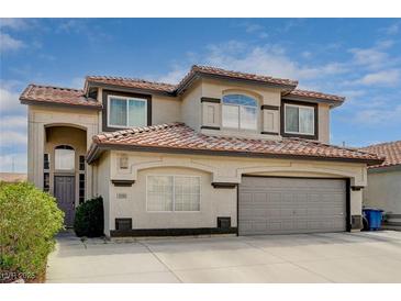 Two-story home featuring a red tile roof, arched entryway, two-car garage, and desert landscaping at 8983 Emerald Waters Ct, Las Vegas, NV 89147