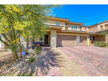 Beautiful two-story home featuring a brick driveway and lush landscaping, creating a welcoming curb appeal at 600 Suncrest Peak Pl, Henderson, NV 89011