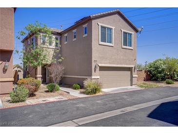 Two-story home featuring a two-car garage and simple xeriscaped yard with bushes and a young tree at 626 Taliput Palm Pl, Henderson, NV 89011