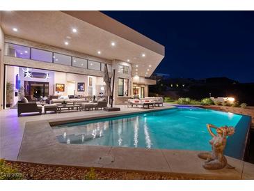 Stunning pool with open floor plan, outdoor seating, and hillside views at night at 661 Dragon Peak Dr, Henderson, NV 89012