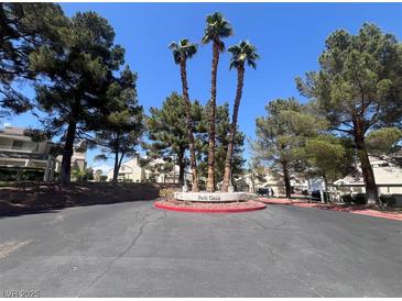 Community entrance featuring mature trees and verdant foliage at 8940 Clairton Ct, Las Vegas, NV 89117